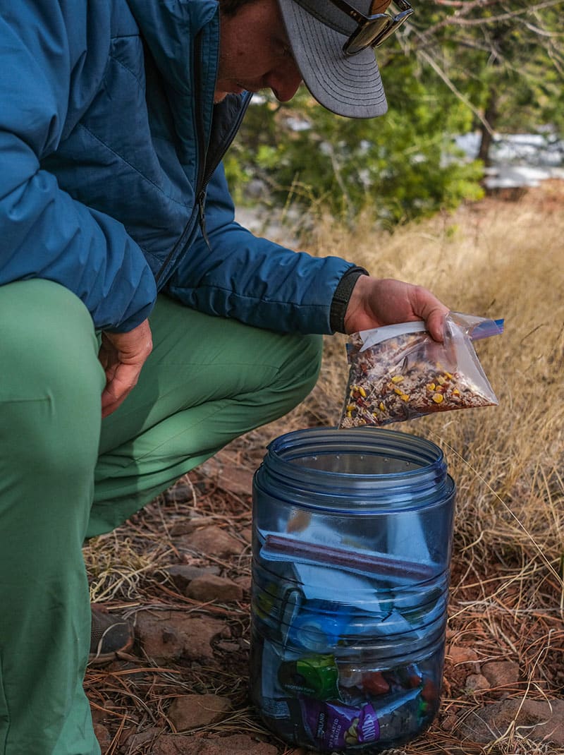 Man putting trail mix in blue bear canister