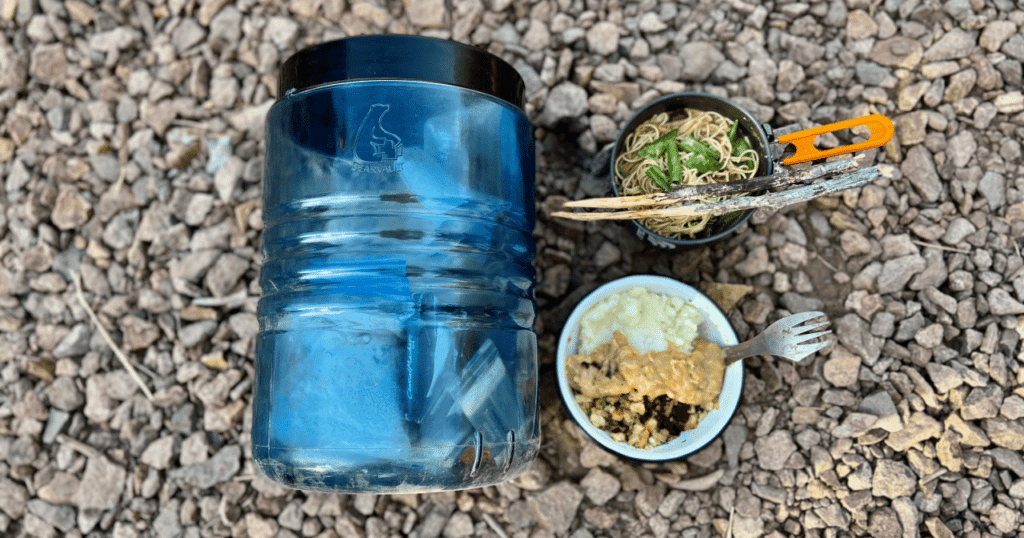 A planned meal sitting on the ground next to a BearVault BV500.