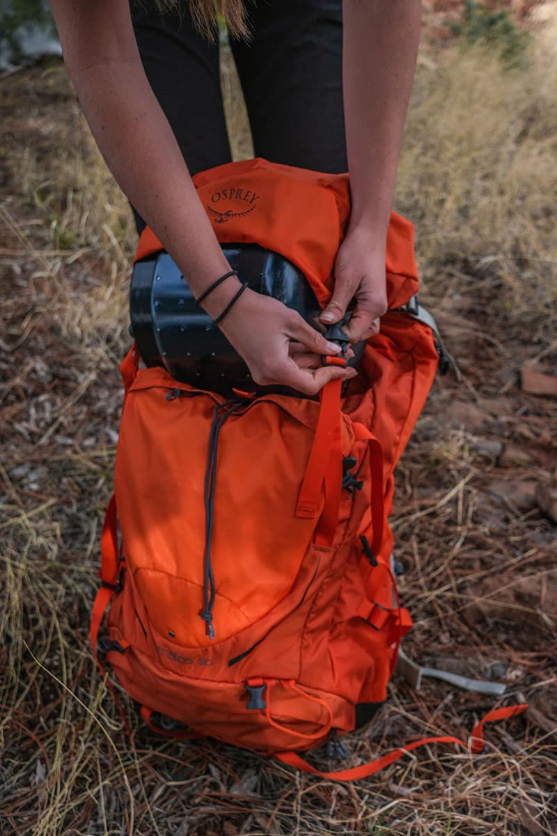 A hiker packing a lightweight backpack.