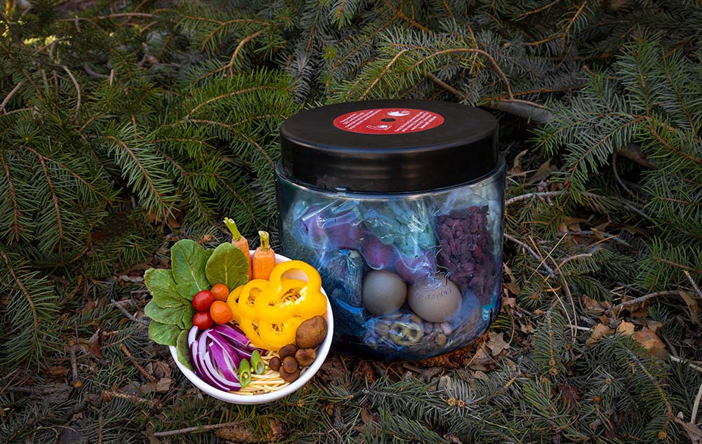 decorative food next to bear canister on pine boughs