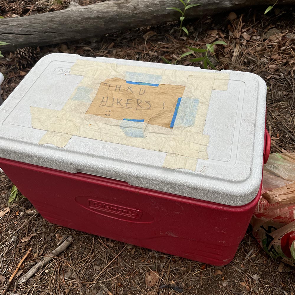 A cooler full of bear food with the sign "Thru-hikers"