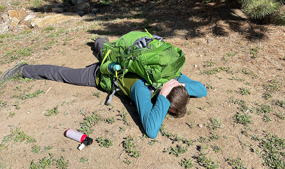 A man lies on the ground protecting himself from a bear attack