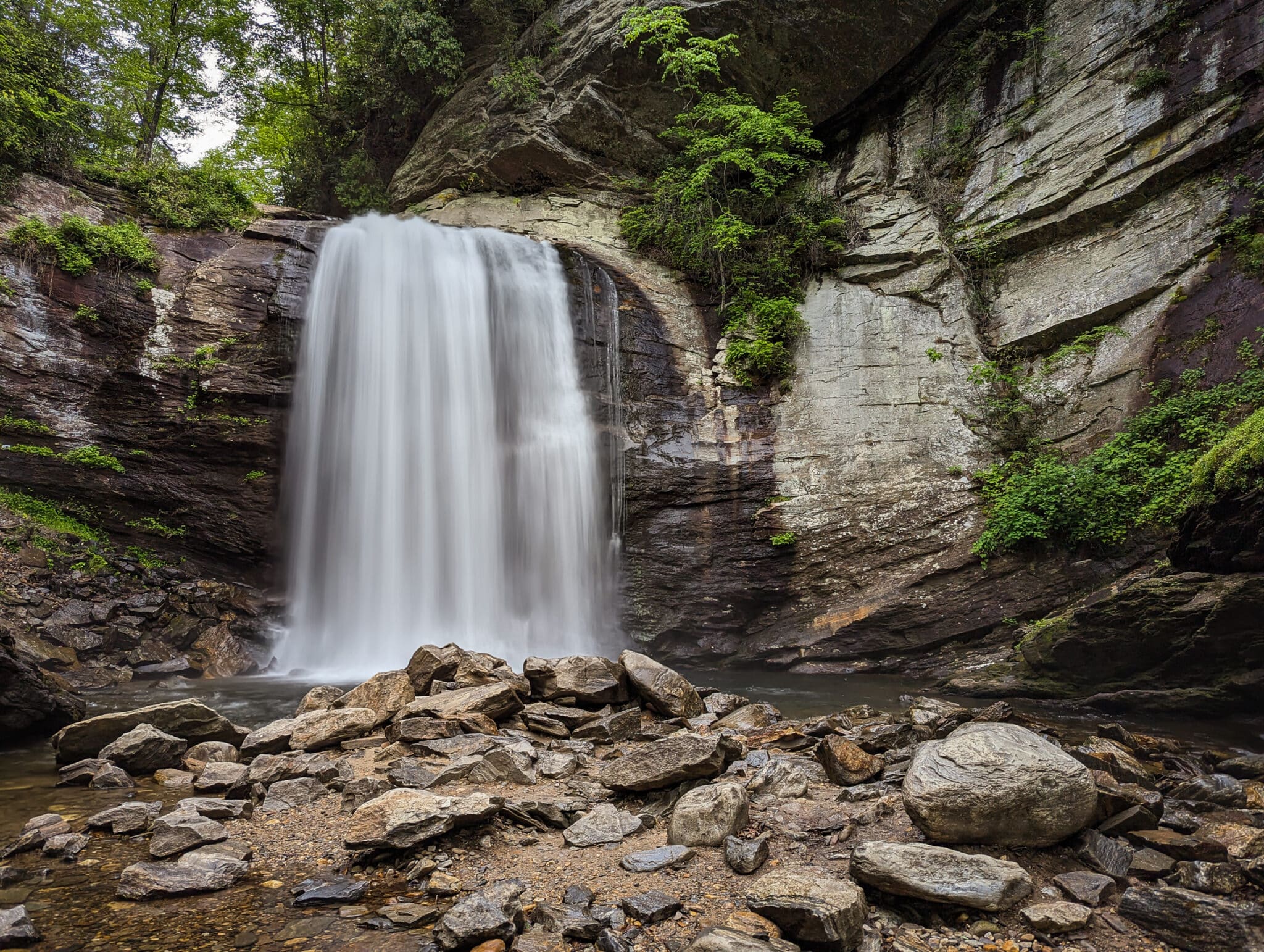 A photo of a waterfall in North Carolina with grey rocks and bright white water