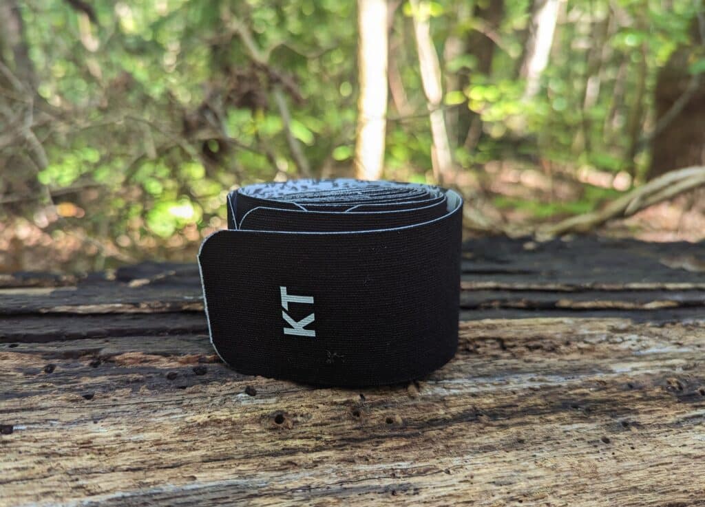 A roll of KTtape sitting on a log in the woods.