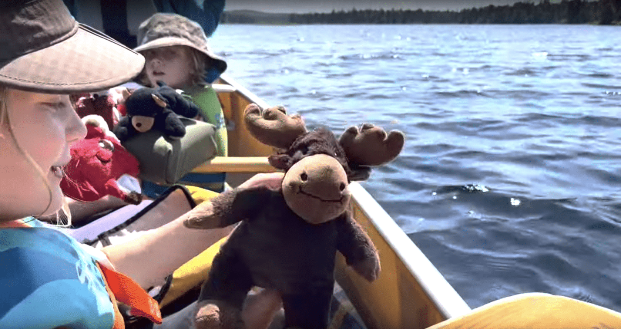 Kids and a stuffed animal moose on a canoe.
