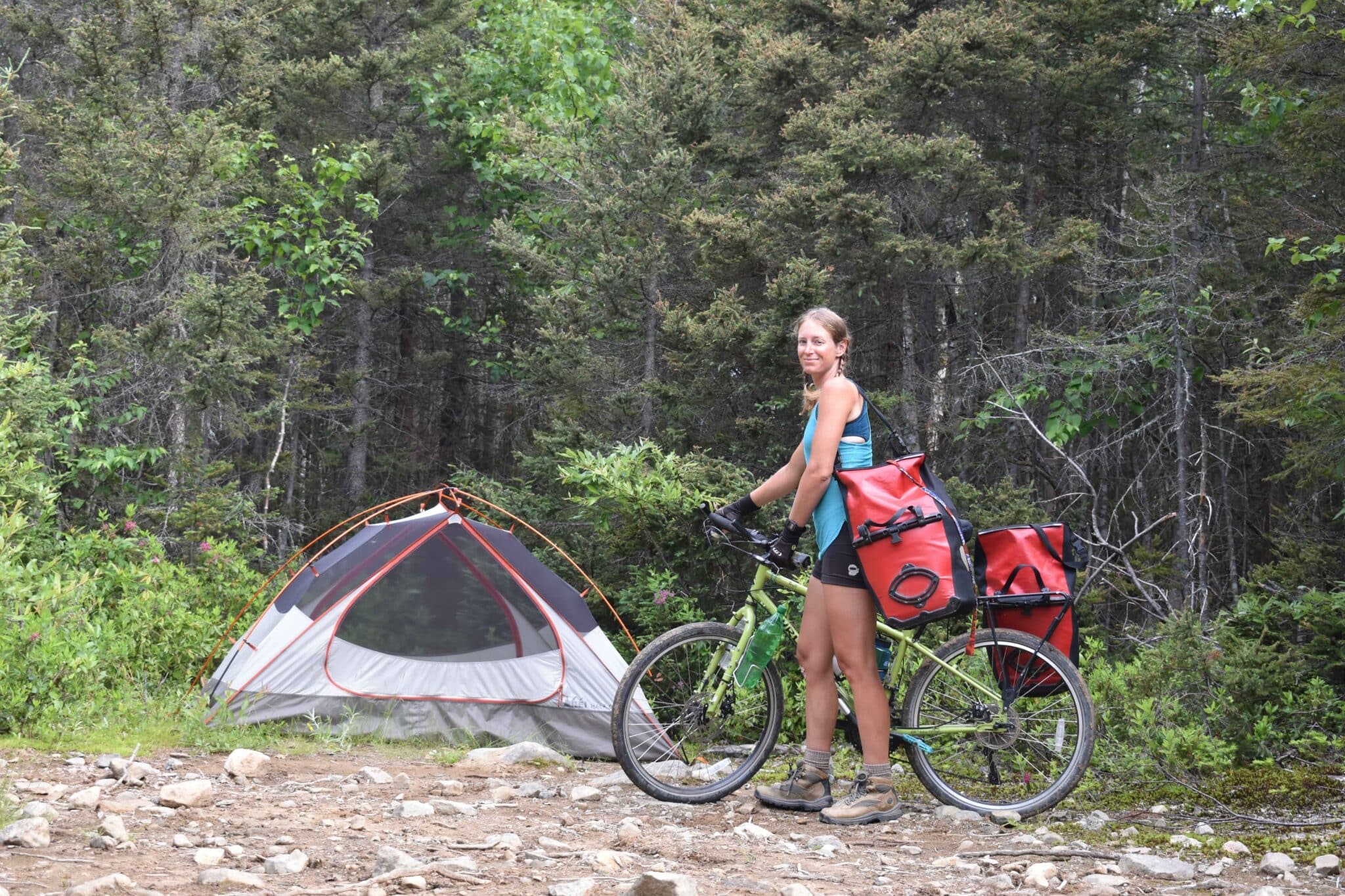 A bikepacker next to a tent in the forest.