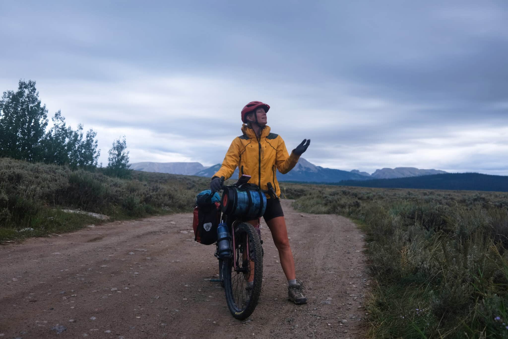 A bikepacker holds out their hand to check if it is raining.