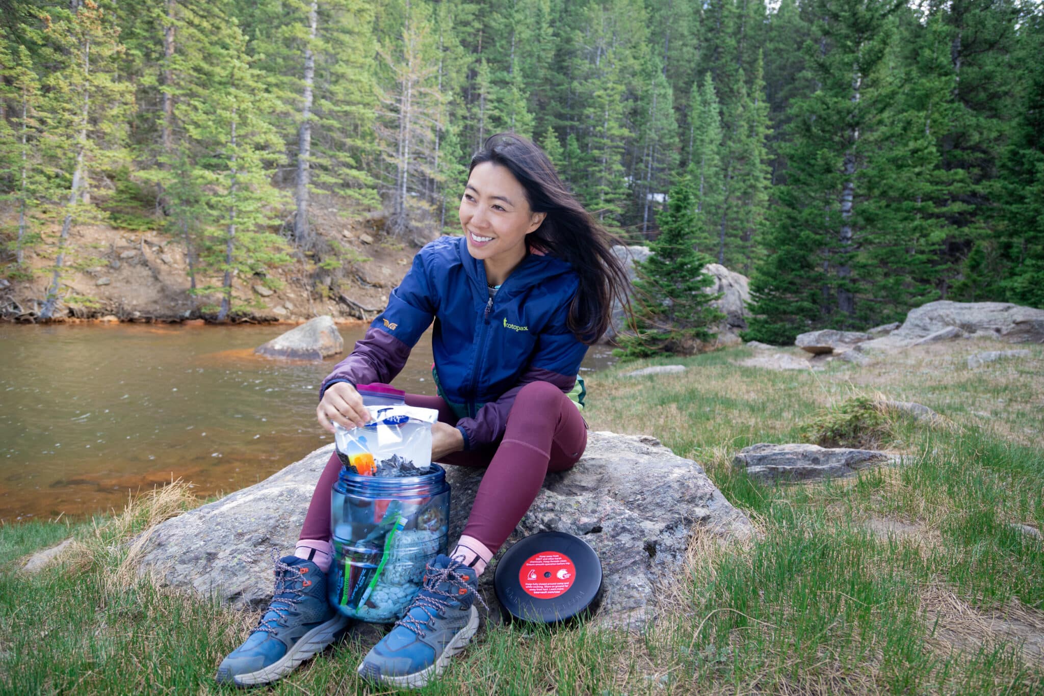 A hiker sitting on a rock unpacks food from a BV475-Trek