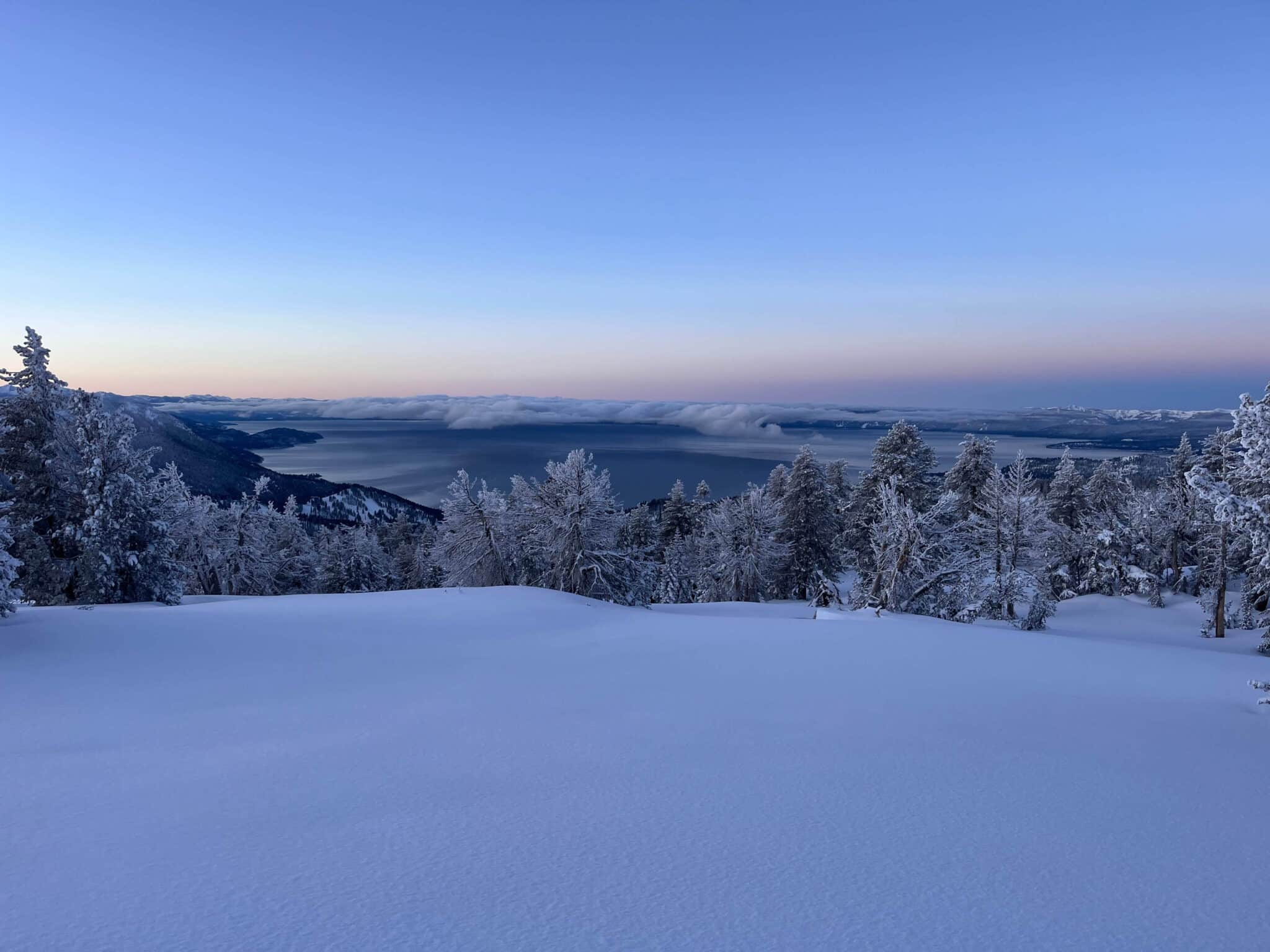 A snowy landscape overlooking Lake Tahoe at dawn