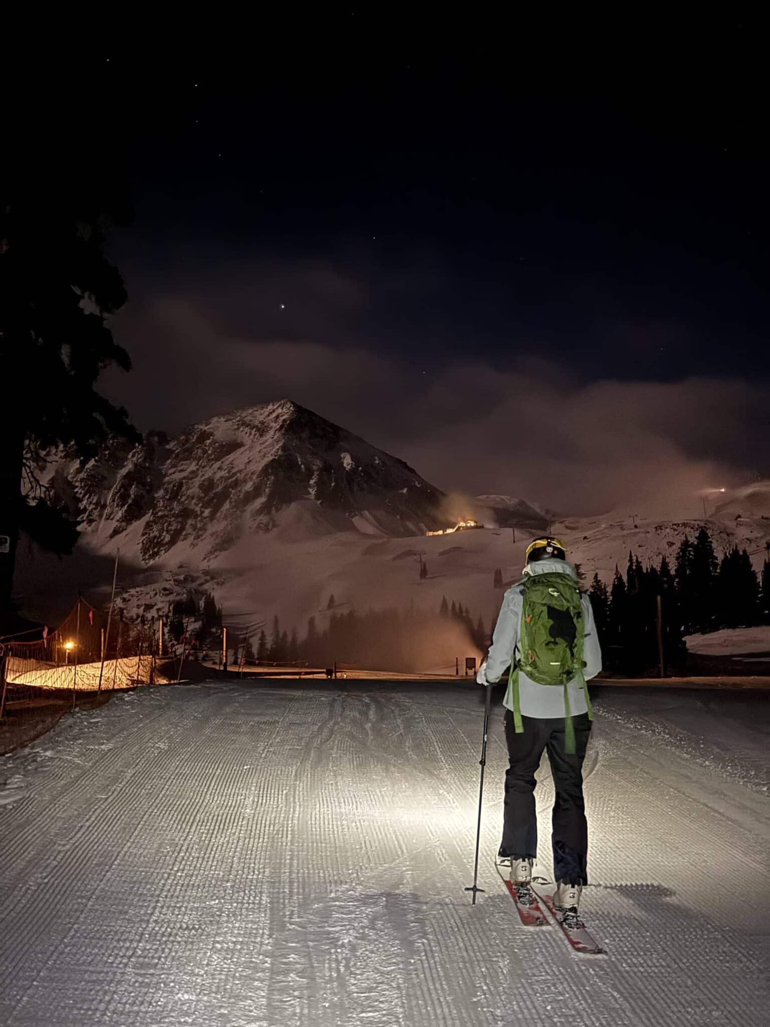 A person skiing in the dark towards a mountain